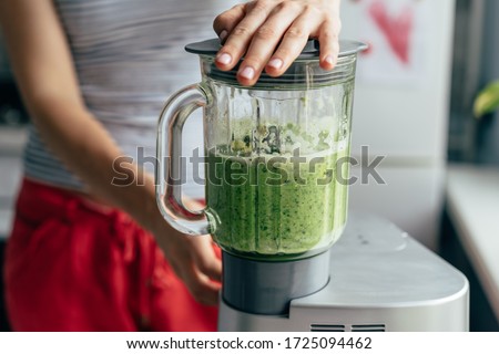 .Close-up blender process. Cooking a green spring smoothie. Mixing in a blender bowl.