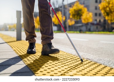 Close-up of a blind man with a walking stick. Walks on tactile tiles for self-orientation while moving through the streets of the city