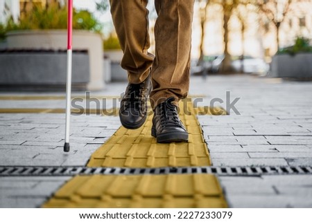 Close-up of a blind man with a walking stick. Walks on tactile tiles for self-orientation while moving through the streets of the city