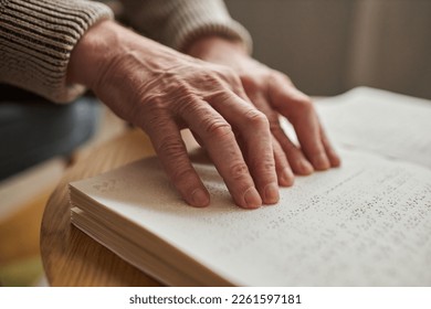 Close-up of blind senior man using his hands to read a book at table - Powered by Shutterstock