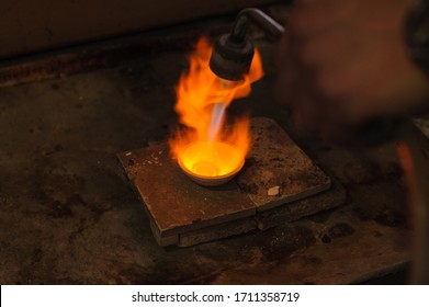 Close-up of a blowtorch heating metal in a crucible, highlighting the intense process in metalworking and foundry work. - Powered by Shutterstock