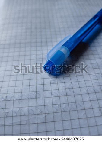 Close-up of a blue ballpoint pen on squared paper, highlighting precision and detail. Ideal for educational content, stationery branding, or artistic expression