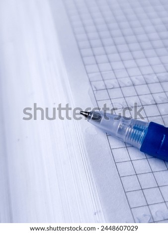 Close-up of a blue ballpoint pen on squared paper, highlighting precision and detail. Ideal for educational content, stationery branding, or artistic expression