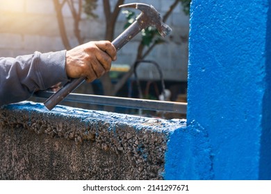 Closeup Of A Blue Collar Worker's Hand Hammering A Steel Pipe While Installing A Fence.