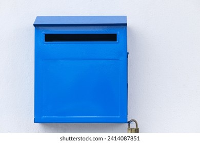 Close-up blue color iron mailbox on square shape that installed on white concrete wall for receive newspaper, letter, document and other from postman or company messenger