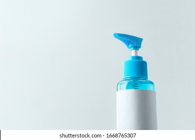 Close-up Blue Isopropyl Alcohol Liquid For Medical Purpose And Anti Coronavirus COVID-19 (Ethanol Or Ethyl Alcohol) In A Plastic Press Pump Head Blue Bottle With Blank Label And Grey White Background.