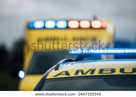 Close-up of blue light flasher on roof of ambulance car of emergency medical service on road. Themes rescue, urgency and health care.	

