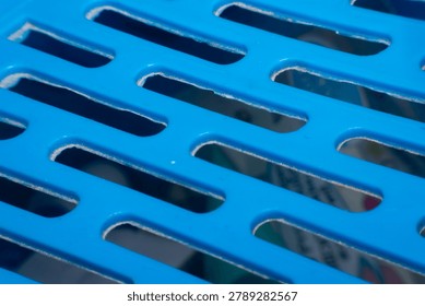 Closeup of blue plastic grid surface showing geometric openings smooth texture industrial design and modern material detail for abstract backgrounds