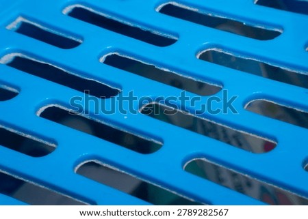 Closeup of blue plastic grid surface showing geometric openings smooth texture industrial design and modern material detail for abstract backgrounds