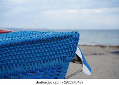 Close-up of the blue plastic wickerwork of a beach chair with a view of the Baltic Sea in the Bay of Luebeck (Lübecker Bucht)                           