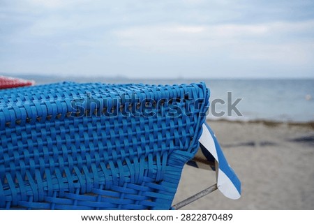 Close-up of the blue plastic wickerwork of a beach chair with a view of the Baltic Sea in the Bay of Luebeck (Lübecker Bucht)                           