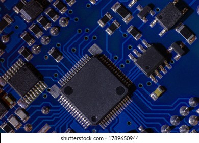 Close-up of a blue printed circuit board (PCB) with stripes of conductors between a transistor and an electronic equipment processor. IT technologies in programming, upgrade and abstract background