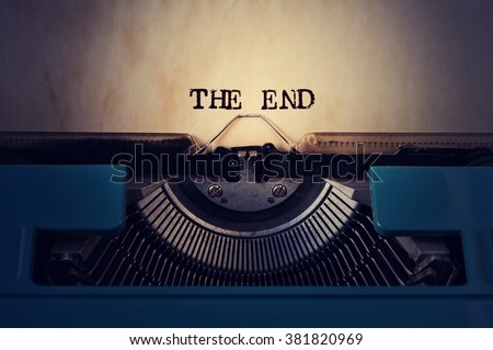 closeup of a blue retro typewriter and the text the end written with it in a yellowish foil