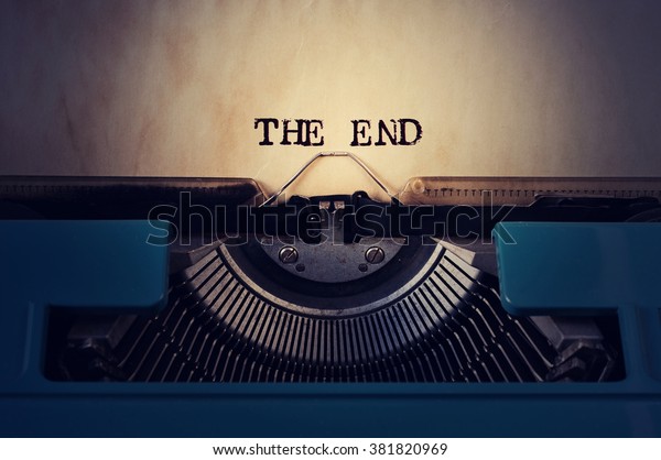closeup of a blue retro typewriter and\
the text the end written with it in a yellowish\
foil