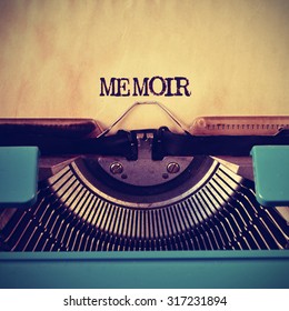 closeup of a blue retro typewriter and the word memoir written with it in a yellowish foil