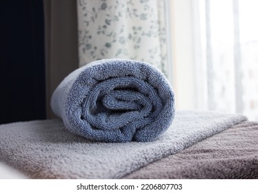 Closeup Of Blue Rolled Bath Towel. Towel A On Table With Copy Space, Blurred Background For Product Display.