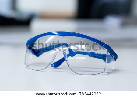 Close-up of blue safety goggles on a desk in a research lab.