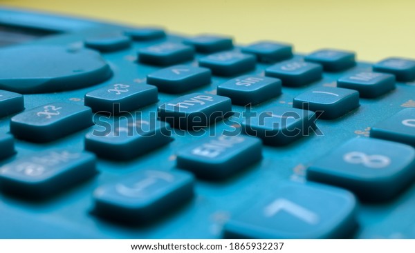 Close-up of a blue\
scientific calculator\'s buttons, over a blurred yellow background.\
Science and maths