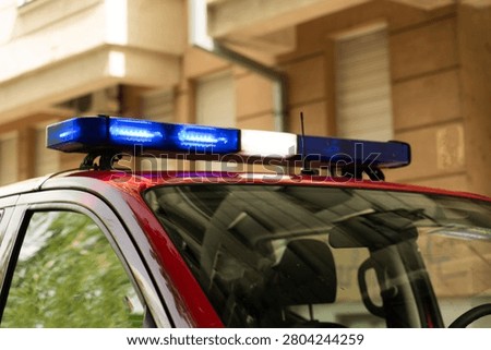 Close-up of blue strobe lights mounted on red vehicle roof, captured in daylight with urban background