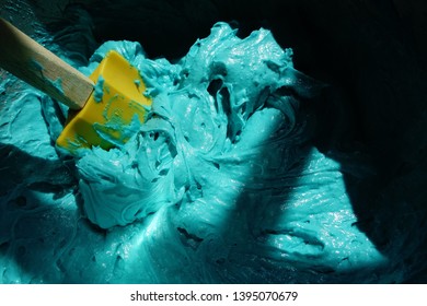 A Close-up Of Blue Velvet Cake Batter In A Bowl With A Yellow Spatula In It