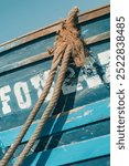 Close-up of a blue weathered wooden fishing boat with frayed rustic ropes tied to its hull, authentic traditional maritime coast scene in the vibrant port of Essaouira, Morocco