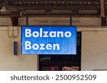 Close-up of blue and white sign at platform of railway station of Italian City of Bozen on a sunny summer day. Photo taken July 17th, 2024, Bolzano Bozen, Italy.