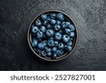 Close-up of blueberries in a bowl on a black slate table.