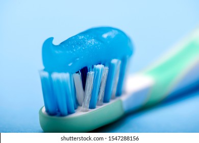 Close-up Of A Blue-hued Toothbrush Shield With Smeared Blue Toothpaste On A Blue Blurred Background