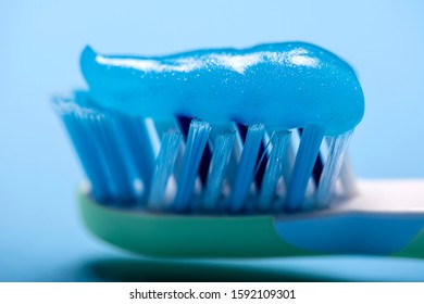 Close-up Of A Blue-hued Toothbrush Shield With Smeared Blue Toothpaste On A Blue Blurred Background