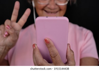 Close-up Of Blurred Senior Woman In Video Call With Her Mobile Phone.  Elderly Retired Enjoying Technology.  Black Background