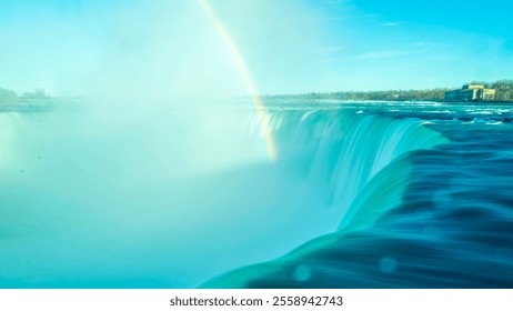 Close-up of the blurred streams of Niagara Horseshoe Falls with bokeh effect. Bright rainbow rises above falls in water cloud. View from Canadian side. Blue sky day. - Powered by Shutterstock