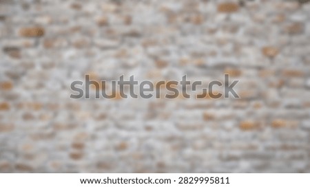 A close-up, blurred view of an old stone wall showing its textured surface and subtle color variations.