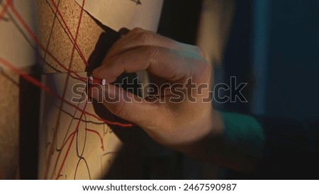 Close-up of board with notes and threads. Stock footage. Man is investigating and fixing evidence on board. Man checks photos and notes on research board