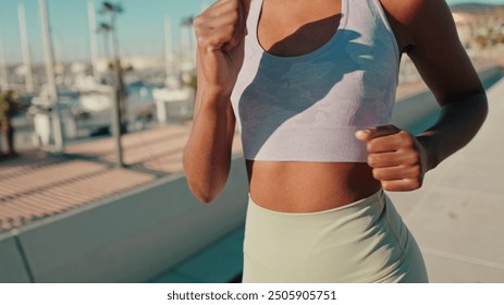 Close-up of body and arms of a girl in sportswear doing street workout, running along the sea - Powered by Shutterstock