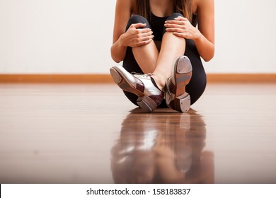 Closeup of the body of a dancer wearing tap shoes and taking a break in a studio