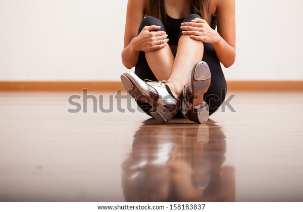 Closeup of the body of a dancer wearing tap shoes\
and taking a break in a\
studio