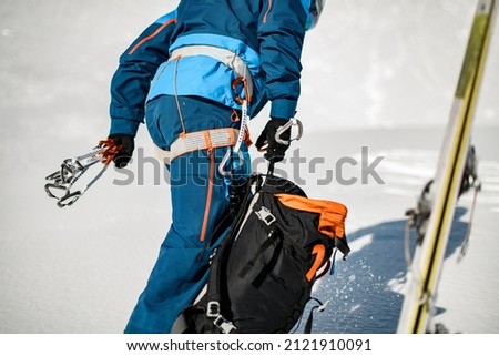 Close-up of the body part of male tourist in ski suit with climbing harness wearing on. Hiking equipment, mountaineering equipment, harnesses.