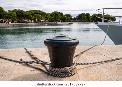 Close-up of a bollard with many ship ropes wrapped around it in the port of the fishing village of Fažana, Croatia - Powered by Shutterstock