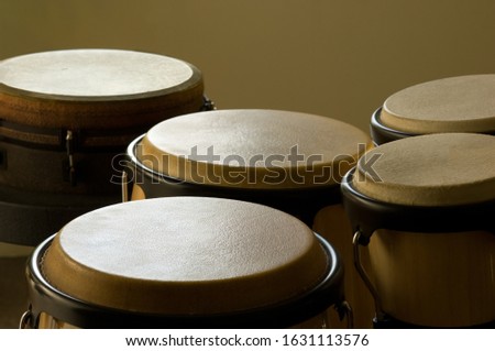 A closeup of bongo drums under the lights against a yellow background