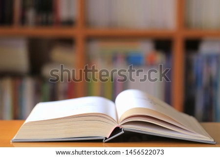 Close-up of books opened on the table in the library bookshelf in the background selective focus and shallow depth of field