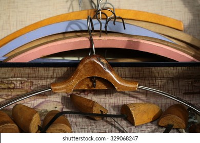 Closeup boot trees and varnish retro wooden coat hanger against lots of vintage clothing hangers angular frames made of timber  painted coloured tired aged background, horizontal picture