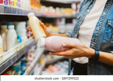 Close-up of bottled dairy products in female hands at grocery store - Shutterstock ID 1897299322