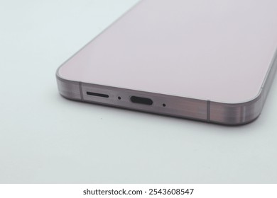 A close-up of the bottom of a lilac smartphone. The phone has a USB-C port and a speaker grille. Isolated on white background. - Powered by Shutterstock