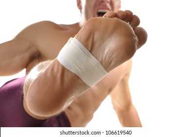 Closeup of bottom of man's foot with middle of foot wrapped with sports tape as he does martial arts kick on white background - Powered by Shutterstock