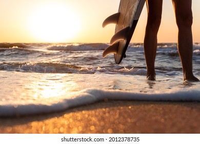 Close-up Bottom Pov View Young Adult Female Surfer Girl Legs With Surfboard Stand At Ocean Coast Wave Against Warm Sunrise Or Sunset Sun. Sport Healthy Carefree Freedom Lifestyle Vacation Concept