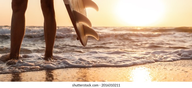 Close-up Bottom Pov View Young Adult Female Surfer Girl Legs With Surfboard Stand At Ocean Coast Wave Against Warm Sunrise Or Sunset Sun. Sport Healthy Carefree Freedom Lifestyle Vacation Concept