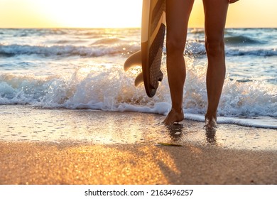 Close-up Bottom Pov View Young Adult Female Surfer Girl Legs With Surfboard Stand At Ocean Coast Wave Against Warm Sunrise Or Sunset Sun. Sport Healthy Carefree Freedom Lifestyle Vacation Concept