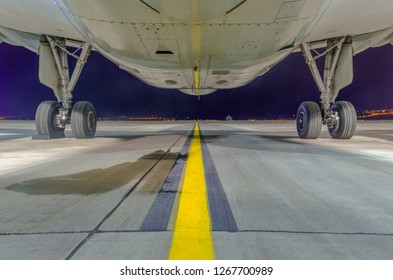 Close-up And Bottom View Of Airbus A320-232 Aircraft's Fuselage And Main Landing Gear At Night. Tbilisi International Airport, Tbilisi, Georgia