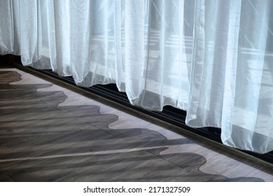 Closeup bottom of white fabric curtain, the glass door is behind, with the shadow and the sunlight coming through to the room 