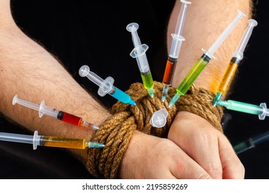 Close-up Bound Hands And Colorful Syringes Stucked From It. Drug Addiction And Hostage Concept.